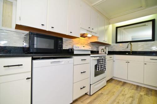 a kitchen with white cabinets and black counter tops at Suns Out Steps to Beach w Private Pool in Cherry Grove in Myrtle Beach