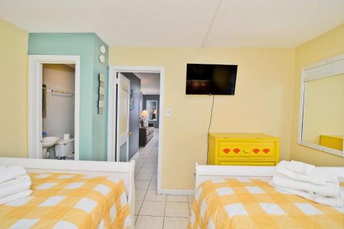 a bedroom with two beds and a television and a bathroom at Suns Out Steps to Beach w Private Pool in Cherry Grove in Myrtle Beach