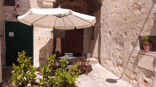 San Biagio Materapartment في ماتيرا: مظلة وكراسي في زقاق مع باب