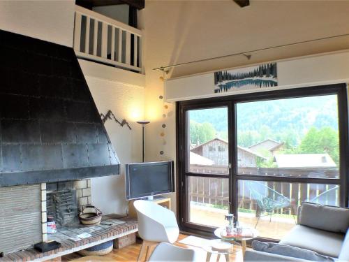 un salon avec une cheminée et une grande fenêtre dans l'établissement Charmant duplex au centre de Samoëns avec balcon, WiFi et parking - FR-1-629-115, à Samoëns