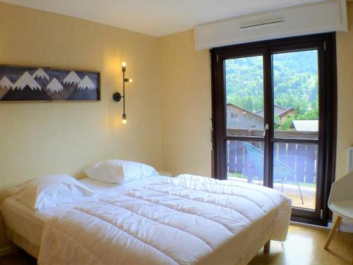 une chambre avec un grand lit et une grande fenêtre dans l'établissement Charmant duplex au centre de Samoëns avec balcon, WiFi et parking - FR-1-629-115, à Samoëns