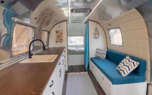 una cucina con divano blu e lavandino di Luxury Vintage Airstream RV/Caravan Retro Charm Meets Comfort a Kiten