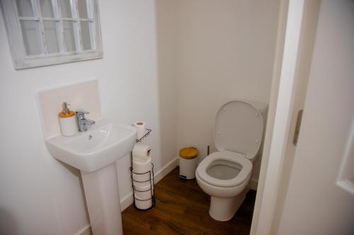 a white bathroom with a toilet and a sink at Beautiful 5 Bedroom House in Glasgow in Cambuslang