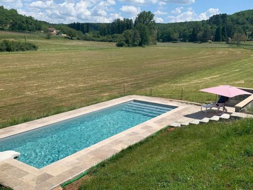 - une piscine dans un champ avec un parasol dans l'établissement Belle maison Vallée du Lot., à Prayssac