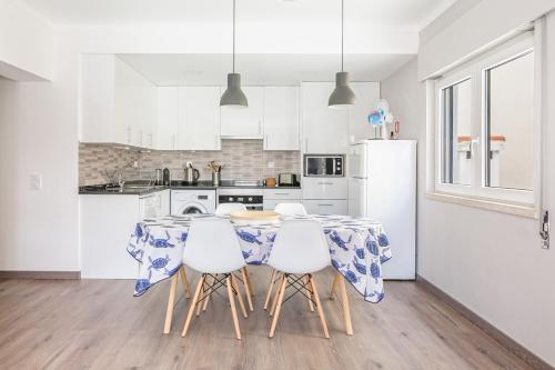 una cucina con tavolo, sedie e frigorifero di 1 Bedroom Beach Apartment with Balcony 2 min walk to the beach! a Costa da Caparica