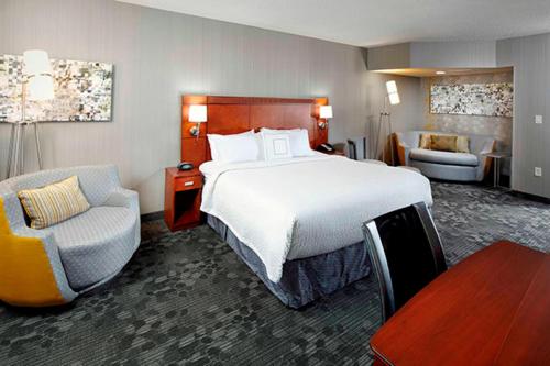 a hotel room with a large bed and a chair at Courtyard by Marriott Akron Stow in Stow