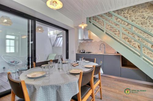 une salle à manger avec une table, des chaises et un escalier dans l'établissement Le Malabar - Les Gîtes de KEROUZEC - Mer et centre historique, à Port-Louis