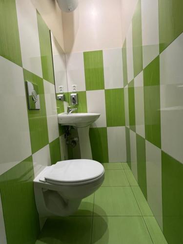 a green and white bathroom with a toilet and a sink at Kust Hostel in Kyiv