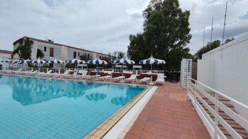 una piscina con sedie e ombrelloni di Residence La Bricola a Sibari