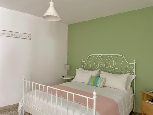 a bedroom with a white bed with a green headboard at Concept Sicily in Siracusa