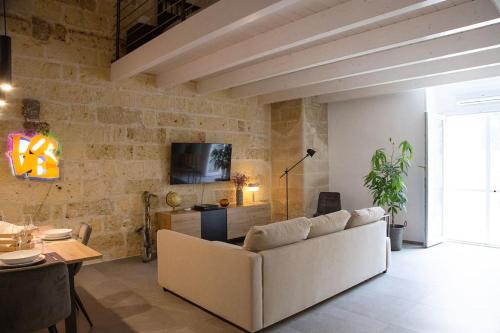 a living room with a white couch and a brick wall at 24 Maggio Apartment in Galatina