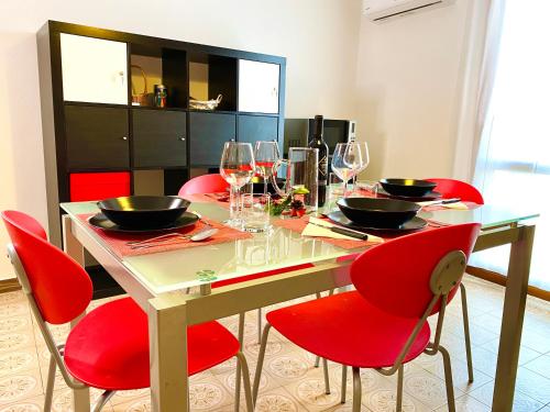 a dining room table with red chairs and wine glasses at HOME - Alessandra Holiday House in Piove di Sacco