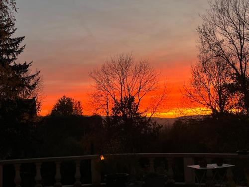 a sunset from a patio with a table and trees at VILLA NOTRE DAME face au Château fort in Sedan