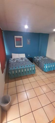 a bedroom with two beds and a blue wall at Hotel Happy House in San Salvador