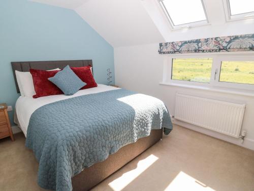 a bedroom with a bed with red pillows and a window at Rose Lodge in Alnwick