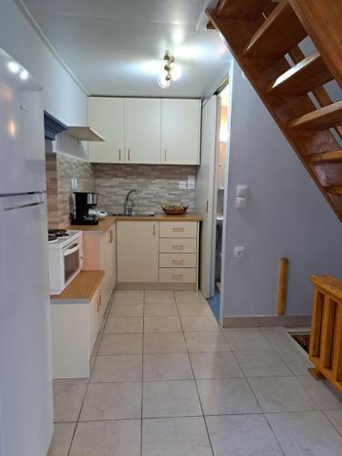 eine Küche mit weißen Schränken und Fliesenboden in der Unterkunft Giasemi traditional house in Poros