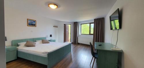 a bedroom with a bed and a desk and a television at Pensiunea Sara pe deal in Hangul