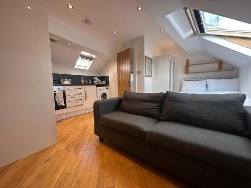 a living room with a black couch and a kitchen at Stunning 1-Bed Studio in Pudsey in Pudsey