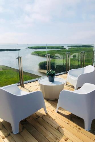 a balcony with white chairs and a view of the ocean at Aitvarai 41 in Svenele