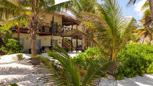 a resort with palm trees in front of a building at Grand Slam Fishing Lodge Tulum in Punta Allen