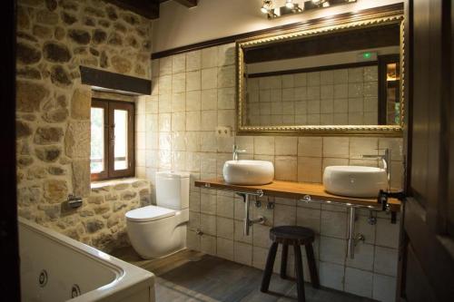 ein Badezimmer mit zwei Waschbecken, einem WC und einem Spiegel in der Unterkunft Casas Rurales La Cuplia in Pedroso