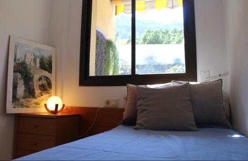 Un dormitorio con una cama azul y una ventana en Barcelo al riu, en Monistrol
