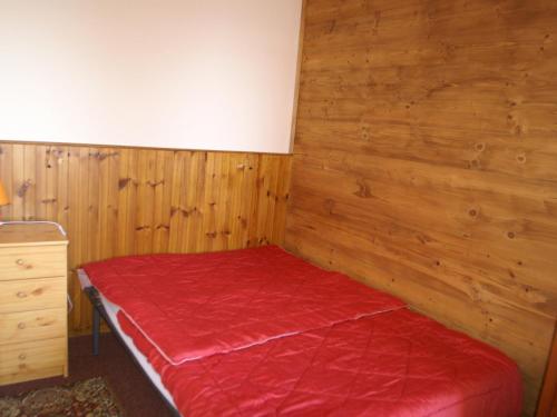 - une chambre avec un lit rouge et des murs en bois dans l'établissement 2 pièces cabine au pied des pistes avec balcon, cuisine équipée et services optionnels - FR-1-557-64, à Les Adrets