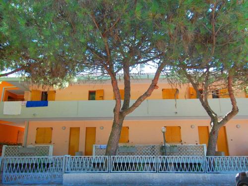 two trees in front of a building with yellow doors at Sun drenched seaside holiday home close to Venice in Rosolina Mare