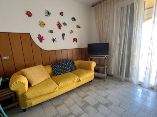 a living room with a yellow couch and a tv at Liguria Holidays- La casa di Sara in Camogli