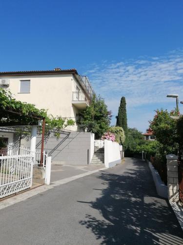 a street in front of a house with a white fence at Lavanda Apartment in Izola
