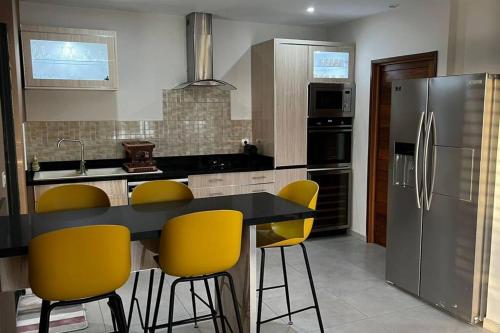 a kitchen with a black counter and yellow chairs at Maya Plage, Villa en bord de mer in Cap Skirring