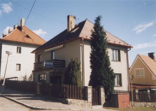 a white house with a fence and a tree at Penzion Zavodsky in Český Krumlov