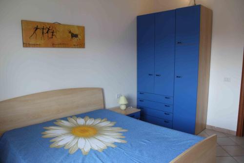a bedroom with a blue dresser and a bed with a flower on it at Appartamenti Marilu in La Caletta