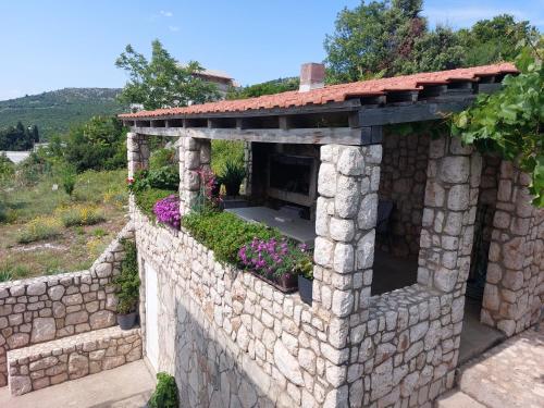 una pared de piedra con flores en un jardín en Apartmani Sunset, en Neum