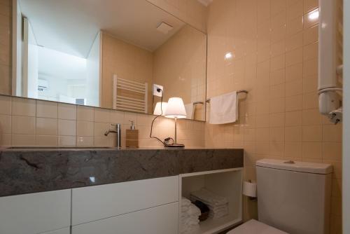 a bathroom with a sink and a toilet and a mirror at Porto Grandeur Collection - D. João IV Pool & Garden Apartment in Porto
