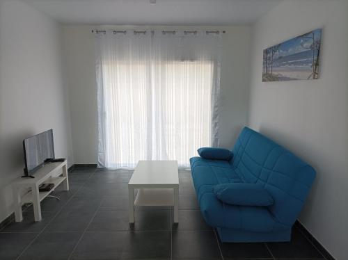 un salon avec un canapé bleu et une table dans l'établissement Maison récente Océadune à Saint-Jean de Monts, à Saint-Jean-de-Monts