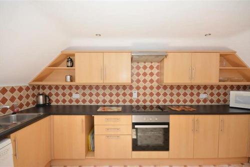 a kitchen with wooden cabinets and a black counter top at Direct Beach Access! Top Floor Apartment Perranporth in Perranporth