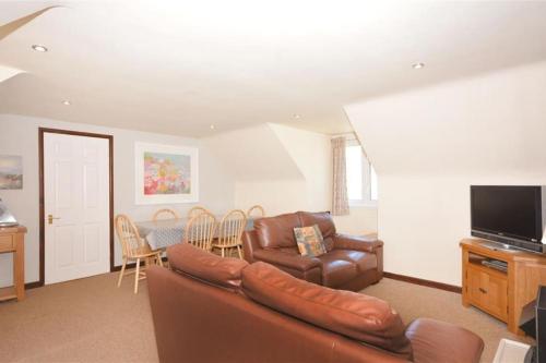a living room with a leather couch and a table at Direct Beach Access! Top Floor Apartment Perranporth in Perranporth