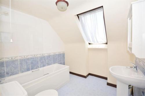 bagno bianco con lavandino, vasca e servizi igienici di Direct Beach Access! Top Floor Apartment Perranporth a Perranporth