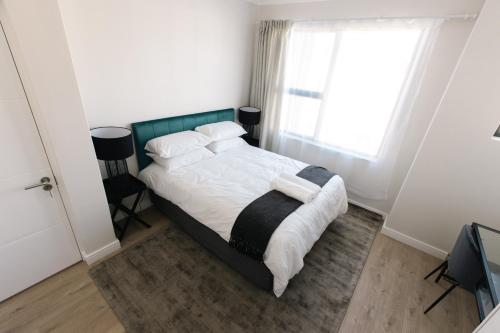 1 dormitorio con 1 cama con sábanas y almohadas blancas en City Nest: Heart of Linksfield en Johannesburgo
