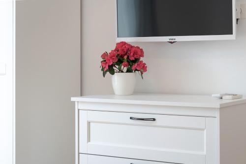 a white cabinet with a vase with red flowers on it at B&B Arba in Barbat na Rabu