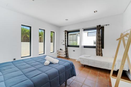 a bedroom with a blue bed and windows at Villa Mateos in Ronda