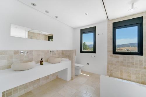 a bathroom with a sink and a toilet and windows at Villa Mateos in Ronda