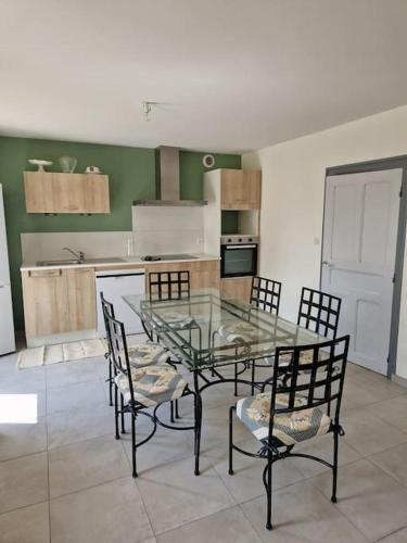 une cuisine avec une table et des chaises en verre dans l'établissement chez Robert, à Bromont-Lamothe