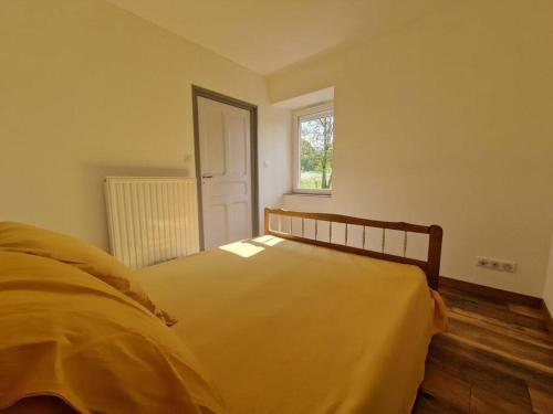 sypialnia z żółtym łóżkiem i oknem w obiekcie maison à la campagne w mieście Bromont-Lamothe