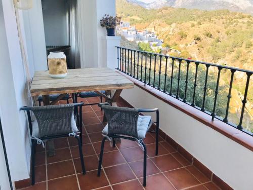 uma varanda com uma mesa de madeira e 2 cadeiras em La Perla de Frigiliana Suites & Villa em Frigiliana