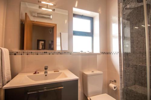 W łazience znajduje się umywalka, toaleta i lustro. w obiekcie Monte Dourado w mieście Carvoeiro