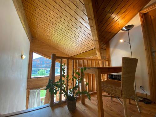 une pièce avec un plafond en bois avec une table et une plante dans l'établissement Duplex chaleureux près du Grand Massif Express avec balcon et garage privé - FR-1-624-33, à Samoëns