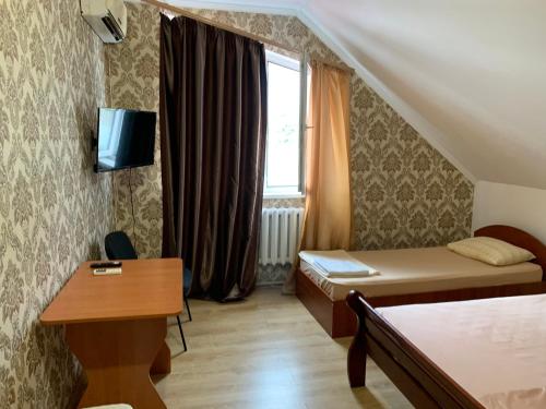 a room with two beds and a desk and a window at Гостиный Дом Comfort in Reni