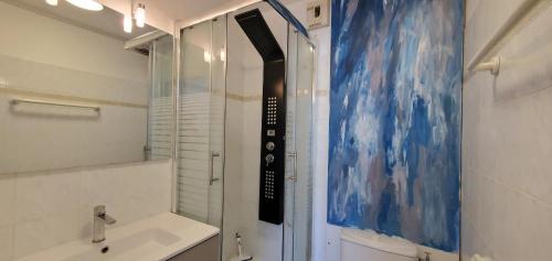 La salle de bains est pourvue d'une douche, d'un lavabo et d'une peinture. dans l'établissement OPEN, T2 42m2, 4 personnes, clim, balcon, piscine, à Fréjus